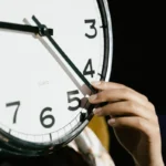 Tangan mengatur waktu pada jam analog besar sebagai ilustrasi perhitungan jam dalam seminggu